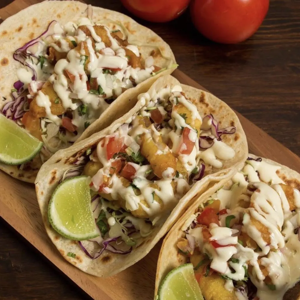 Baja style fish tacos with beer-battered red snapper, white sauce, cabbage and lime